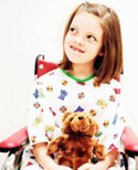 Little girl in wheelchair holds teddy bear